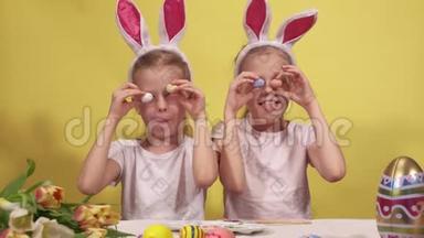 可爱的姐妹，有兔子的耳朵，在复活节准备的时候，眼睛旁边放着五颜六色的鹌鹑蛋
